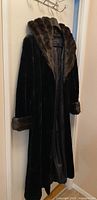 Front view of full-length black coat on hanger