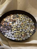 Overhead view of round tray filled with mixed foreign coins