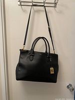 Front view of black leather RLL satchel with shoulder strap and handles