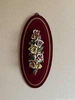 Full view of oval velvet plaque with porcelain flowers