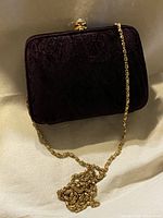 Front view of purple velvet clutch with gold chain