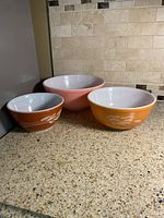 Three Pyrex bowls side-by-side showing sizes and colors
