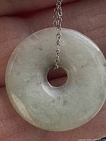 Close-up of light green jade donut pendant on chain