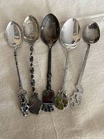 Front view of five sterling souvenir spoons showing bowls and finials