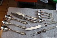 Full view of all 11 silver flatware pieces arranged on towel