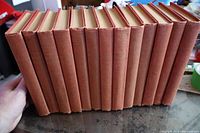 All 13 red cloth hardcover volumes standing edge-on