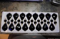 Tray holding 16 black faceted chandelier crystals in two pieces each