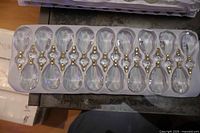 Tray holding eleven faceted teardrop chandelier crystals with gold pins