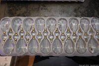 Tray holding seventeen clear faceted drop crystals with gold-tone connectors