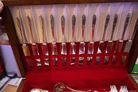 Open chest lid showing twelve dinner knives in rack