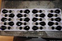 Tray holding 20 black glass chandelier prisms
