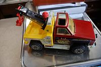 Side view of Tonka tow truck showing red cab, yellow bed, black boom