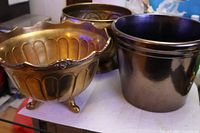 Three planters grouped: ornate footed brass, plain brass, glazed terracotta
