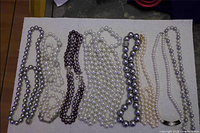All eight necklaces laid out side by side on white board