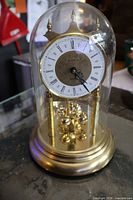 Front view of Birks brass anniversary clock under glass dome