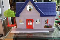Front exterior of Fisher-Price playhouse showing roof, numbered door and swing