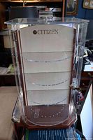 Full view of Citizen display cabinet showing clear sides, wood base, rotating shelves