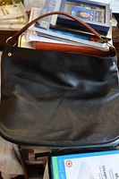 Front view of black leather shoulder bag showing overall appearance and strap