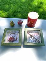 Group shot of both framed prints, two ceramic fruits and red metal tin