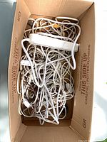 Box containing tangled white cords and power strips