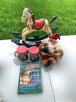 Group shot showing wooden rocking horse, pair ceramic shakers, plush Santa, and hardcover book