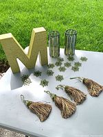 All items laid out: letter M, two candle holders, twelve beaded snowflakes, four tassels