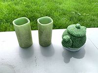 Two green LED candles and green ceramic teapot figurine on table