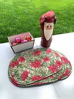 All items together on table: wooden Santa, box with ornaments, placemats