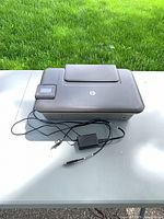 Top view of HP DeskJet 3052A printer with power adapter and USB cable