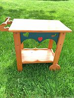 Full view of wood serving cart showing two tiers, wheels, handle, heart cut-outs