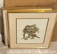 Front view of one framed bird print, gold frame and mat detail visible, second frame behind