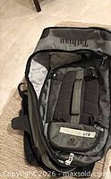 Front view of gray/black Tathian backpack showing padded straps and embroidered logo