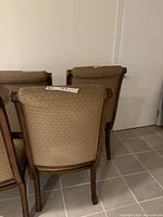 Rear view of three chairs showing wood frames and upholstery