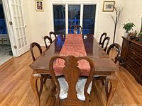 Mahogany dining table with eight chairs around it, showing cabriole legs and upholstered seats