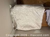 Folded ivory satin-like curtain panel showing floral stitched pattern