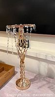 Full view of one gold metal candle holder with hanging crystals
