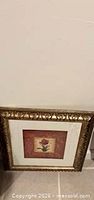 Front view of gold ornate framed square floral print
