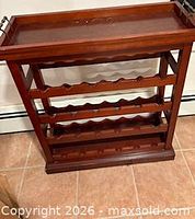 front view of wood wine rack showing tray and three scalloped shelves