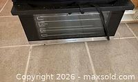 Front view of black and stainless countertop toaster oven with cord visible