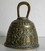 front view of brass bell showing relief figures and handle