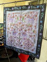 Full view of embroidered wall hanging on rod