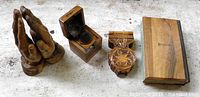 Four olive wood religious items laid out: praying hands figure, incense burner box closed, host dispenser, small Bible