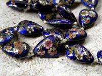 Close-up showing floral cloisonné detail on royal blue teardrop beads