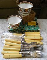 Group shot showing fish cutlery set, boxed knives, two teacups stacked on boxes