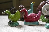 Close-up of green and pink duck figurines with others behind