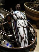 Front view of bronze enamel angel figure among other jewellery (background not part of lot)