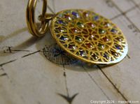 Close-up of gold pendant showing coloured enamel mosaic