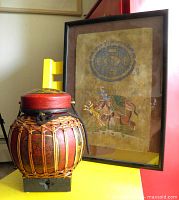 Overall view of framed painting next to bamboo rice bucket