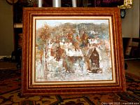 Front view of framed oil painting showing winter village scene and full wooden frame