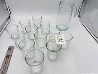 Pitcher and twelve glasses arranged with ruler for scale